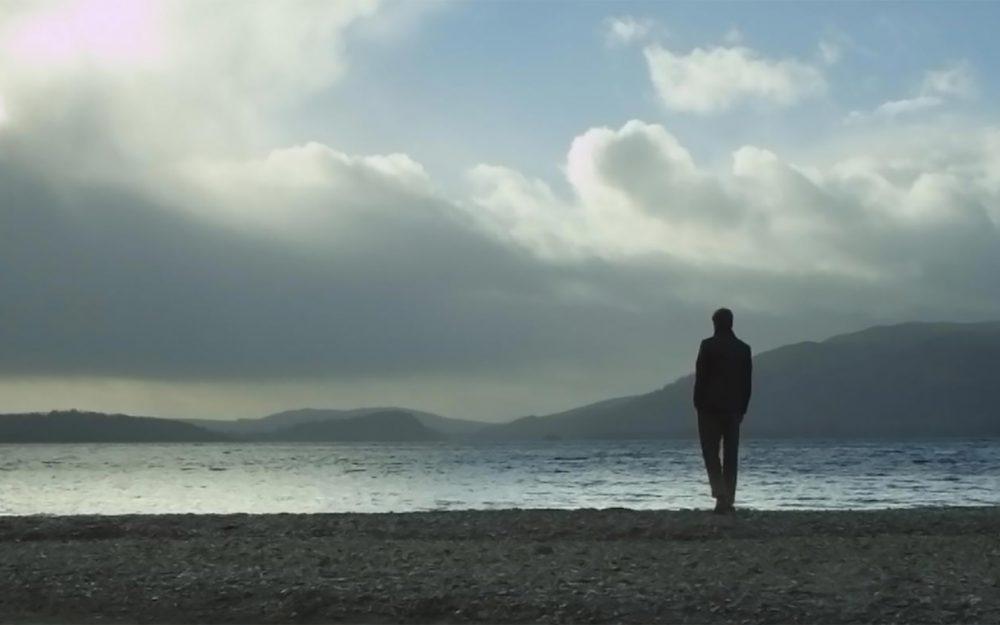 The man stands in front of the lake